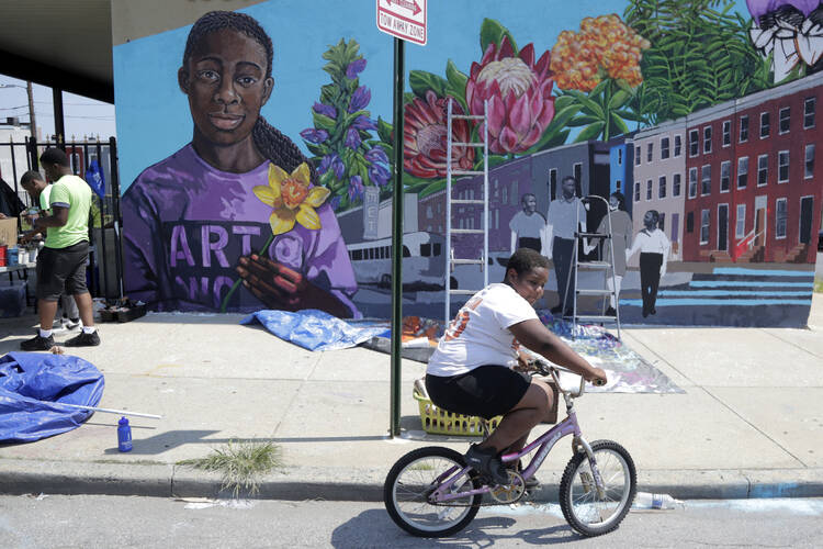 A boy rides his bicycle on July 29 after volunteering to paint a mural outside the New Song Community Church in the Sandtown section of Baltimore. In the latest rhetorical shot at lawmakers of color, President Donald Trump over the weekend vilified Rep. Elijah Cummings majority-black Baltimore district as a "disgusting, rat and rodent infested mess" where "no human being would want to live." (AP Photo/Julio Cortez)