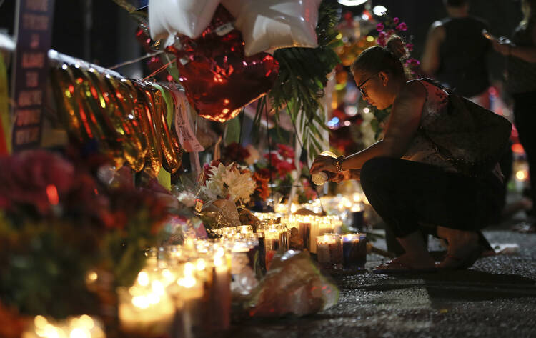 Roxana Jaquez lights a candle at an ever growing memorial Monday, Aug. 5, 2019, outside the Walmart in El Paso, Texas, where a mass shooting took place on Saturday. 