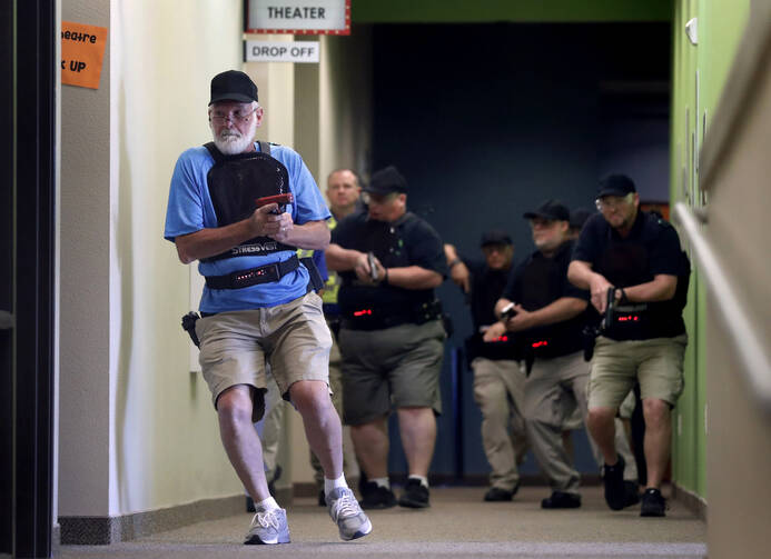 Stephen Hatherley, left, leads fellow trainees down a hallway as they participate in a simulated gun fight scenario at Fellowship of the Parks campus in Haslet, Texas. (AP Photo/Tony Gutierrez)