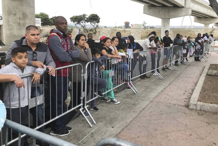 Asylum seekers in Tijuana, Mexico, listen to names being called from a waiting list at a border crossing in San Diego on Sept. 26. (AP Photo/Elliot Spagat,File)