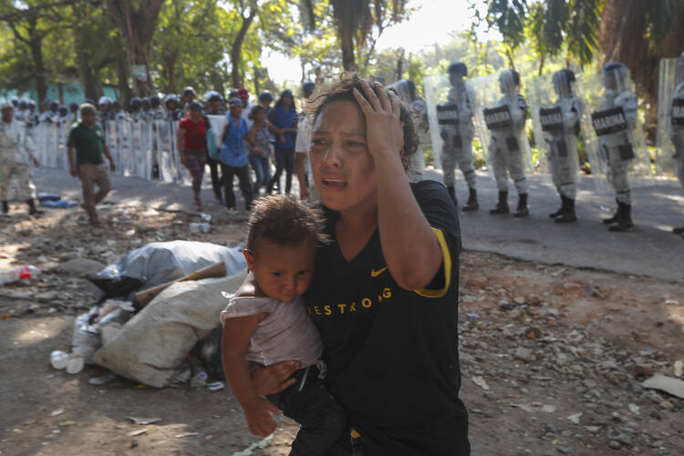 A female migrant carrying a child moves away from Mexican National Guards blocking the passage of a group of Central American migrants near Tapachula, Mexico, Thursday, Jan. 23, 2020. Hundreds of Central American migrants crossed the Suchiate River into Mexico from Guatemala Thursday after a days-long standoff with security forces. (AP Photo/Marco Ugarte)