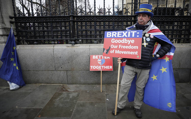 Anti-Brexit campaigner Steve Bray holds banners as he stands outside Parliament in London on Jan. 30, 2020. Although Britain formally leaves the European Union on Jan. 31, little will change until the end of the year. (AP Photo/Kirsty Wigglesworth)