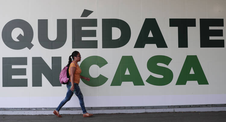 In Mexico City on March 31 a woman walks past a sign that urges: “Stay home.” Mexico's government broadened its shutdown of “non essential activities” and prohibited gatherings of more than 50 people to help slow down the spread of the new coronavirus. (AP Photo/Eduardo Verdugo)