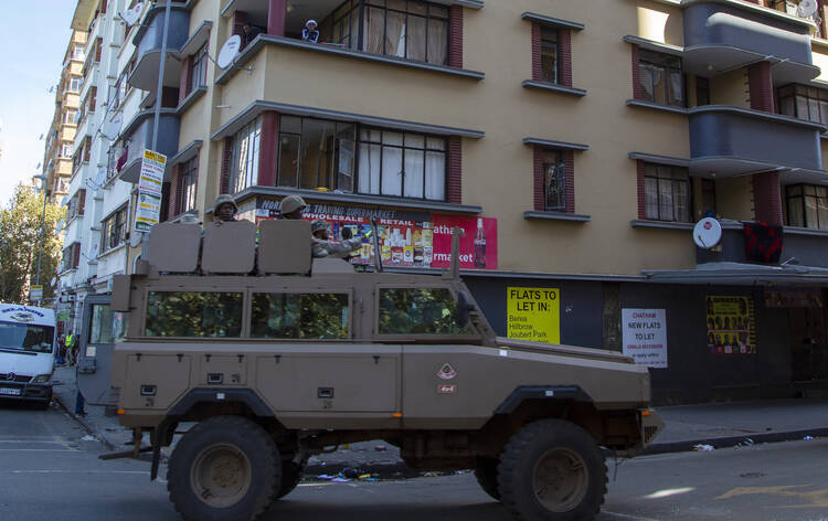 Residents stand on a balcony as a South African National Defence Forces vehicle patrol the street, in Johannesburg on April 7. South Africa and more than half of Africa's 54 countries have imposed lockdowns, curfews, travel bans or other restrictions to try to contain the spread of COVID-19. (AP Photo/Themba Hadebe)