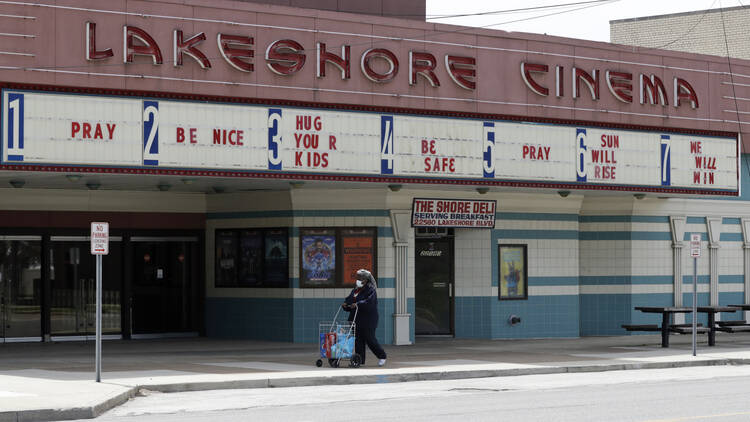 Should the U.S. reopen all at once or one screen at a time? A woman walks past the closed Lakeshore Cinema in Euclid, Ohio, on May 6. (AP Photo/Tony Dejak)