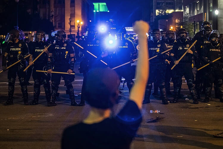 A line of police officers faces a woman participating in a protest on May 29 in Louisville, Ky., of the killing of Breonna Taylor by police in March. (Michael Clevenger/Courier Journal via AP)