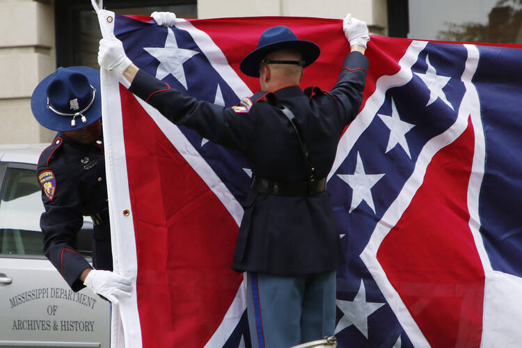 A Mississippi Highway Safety Patrol honor guard folds the retired Mississippi state flag after it was raised over the Capitol grounds one final time in Jackson, Miss., on July 1. (AP Photo/Rogelio V. Solis)