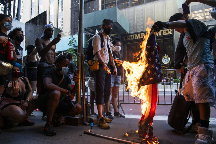 Protesters burn U.S. flags during a protest in front of Trump Tower, Saturday, July 4, 2020, in New York. (AP Photo/Eduardo Munoz Alvarez)