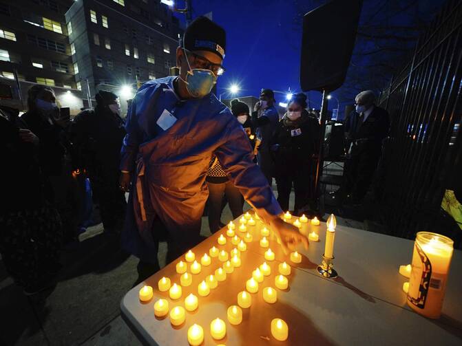 Health service workers light candles during a vigil for coronavirus victims at Elmhurst Hospital in Queens, New York, on April 16. (Photo by John Nacion/STAR MAX/IPx 2020)