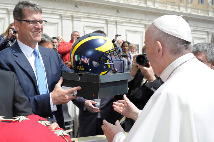 Pope Francis is presented with a football helmet by Michigan football team coach Jim Harbaugh during the weekly general audience at the Vatican, Wednesday, April 26, 2017. (L'Osservatore Romano/Pool Photo via AP)