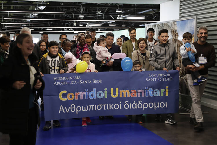 Refugees sponsored by the Vatican and the Sant’Egidio Community hold a banner supporting “Human Corridors” upon their arrival at Fiumicino airport on Dec. 4. (AP Photo/Alessandra Tarantino)