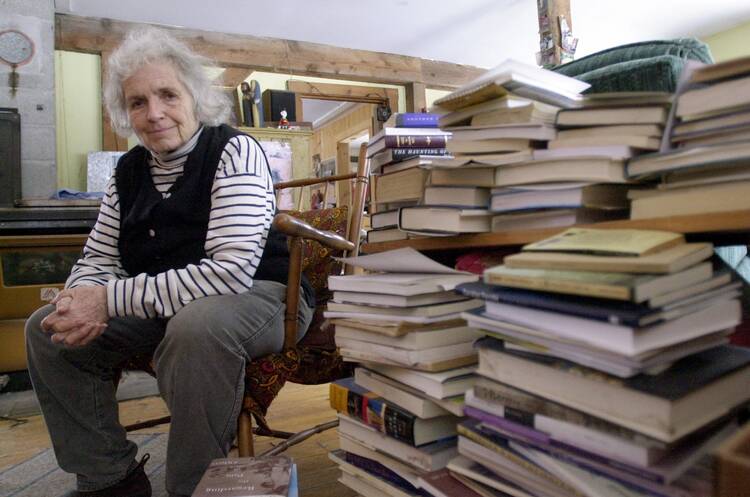 Grace Paley sits beside a pile of books in her home in Thetford Hill, Vt., April 9, 2003 (AP Photo/Toby Talbot).