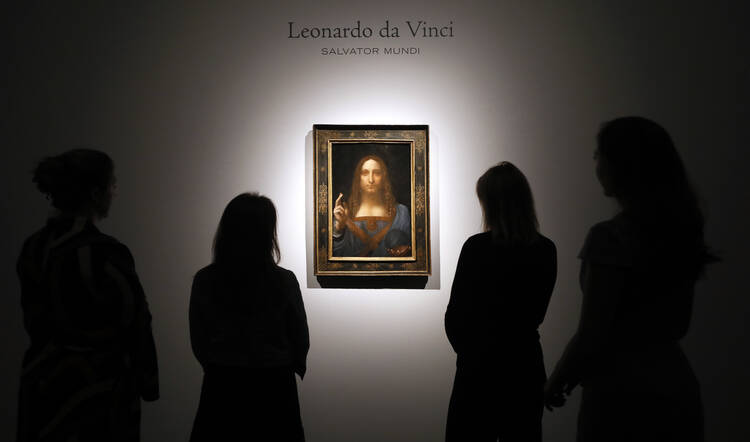 People gather around Leonardo da Vinci's 'Salvator Mundi' on display at Christie's auction rooms, in London, Tuesday, Oct. 24 (AP Photo/Kirsty Wigglesworth).