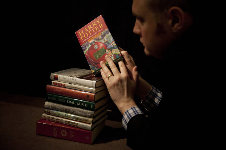 In this Monday, May 20, 2013 file photo, Sotheby's director of the department of printed books and manuscripts Dr Philip Errington poses for photographers by holding a first edition copy of the first Harry Potter book "Harry Potter and the Philosopher's Stone" containing annotations and illustrations by author J.K. Rowling on top of a stack of other annotated first edition books featuring at auction, at the auction house's premises in London. (AP Photo/Matt Dunham, File)