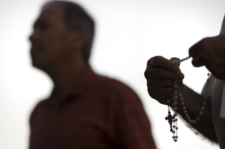 An attendee prays the rosary Oct. 1 during a public session on the issue of clergy sexual abuse at Our Mother of Confidence Parish Hall in San Diego. (CNS photo/David Maung) 