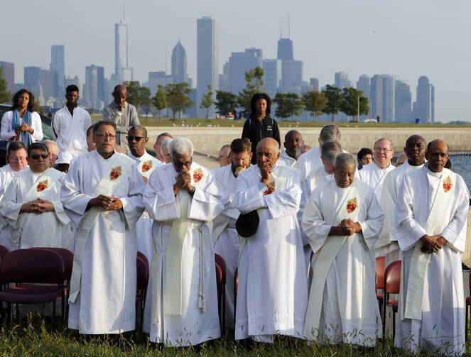 With the Chicago skyline in the background, deacons pray as participants gather to end violence and promote peace during the eighth annual Sunrise Prayer Service and Mass on Aug. 26, 2017. (CNS photo/Karen Callaway, Chicago Catholic)