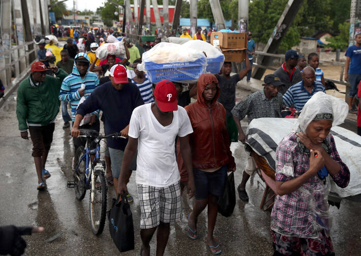 People cross a bridge over a rushing river as part of evacuations during Hurricane Matthew Oct. 4, 2016 in Port-au-Prince, Haiti (CNS photo/Orlando Barria, EPA).