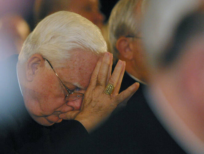 Boston Cardinal Bernard F. Law bows his head as a victim of clergy sexual abuse begins to address the U.S. bishops in 2002 in Dallas (CNS photo by Bob Roller).