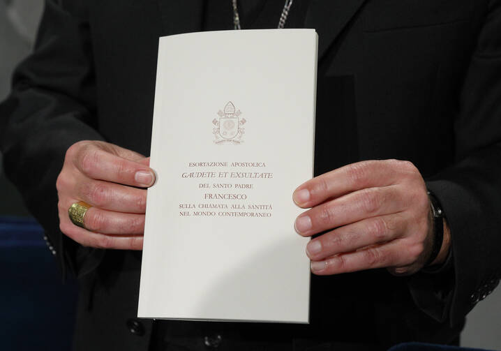 Archbishop Angelo De Donatis, papal vicar for the Diocese of Rome, holds a copy of Pope Francis' exhortation, "Gaudete et Exsultate" ("Rejoice and Be Glad"), during a news conference on the exhortation at the Vatican April 9. (CNS photo/Paul Haring)