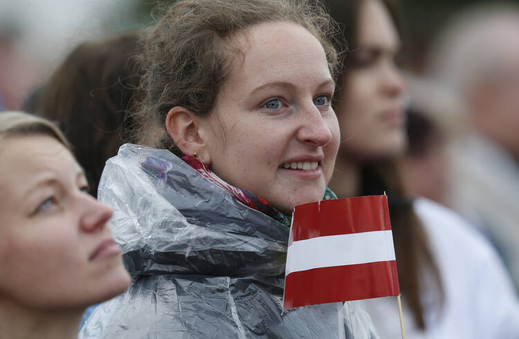  A young woman holds the Latvian flag as Pope Francis celebrates Mass Sept. 24 at the Shrine of the Mother of God in Aglona, Latvia. (CNS photo/Paul Haring) 
