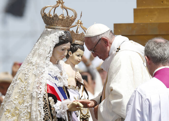 Pope Francis touches a statue of Mary and Jesus after crowning it during Mass at Lobito beach in Iquique, Chile, Jan. 18. (CNS photo/Paul Haring) 