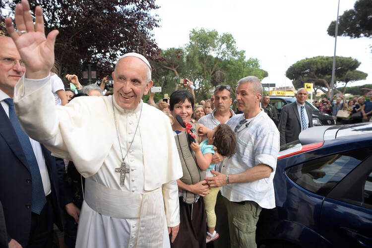 Pope Francis waves during a visit to give an Easter blessing to homes in a public housing complex in Ostia, a Rome suburb on the Mediterranean Sea, May 19 (CNS photo/L'Osservatore Romano).