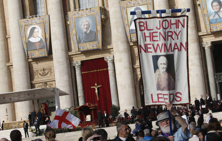  A man holds a banner showing new St. John Henry Newman before the canonization Mass for five new saints celebrated by Pope Francis in St. Peter's Square at the Vatican Oct. 13, 2019. (CNS photo/Paul Haring)