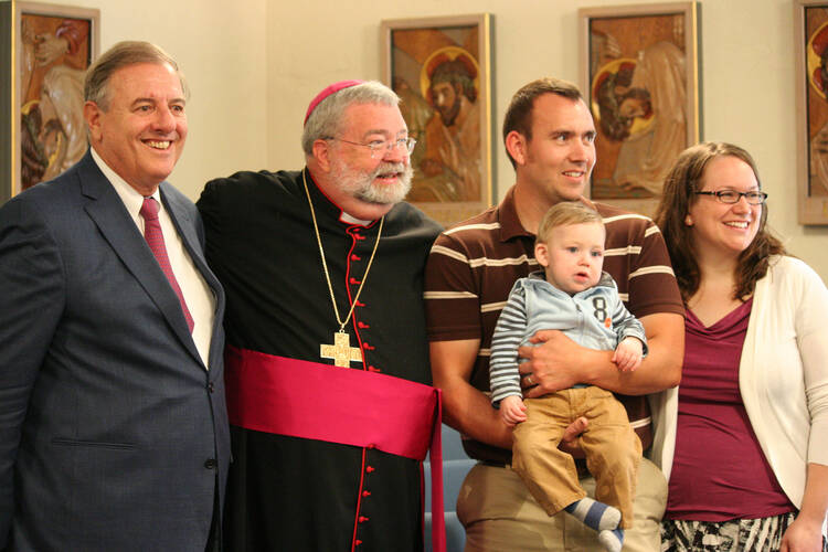 James Fulton Engstrom is held by his parents, Travis and Bonnie Engstrom, Sept. 7, 2011, at the Spalding Pastoral Center in Peoria, Ill., as a tribunal began investigating the boy's miraculous healing through the intercession of Archbishop Fulton J. Sheen. With them are Andrea Ambrosi, postulator of Archbishop Sheen's sainthood cause, and Peoria Bishop Daniel R. Jenky. (CNS photo/Jennifer Willems, The Catholic Post)