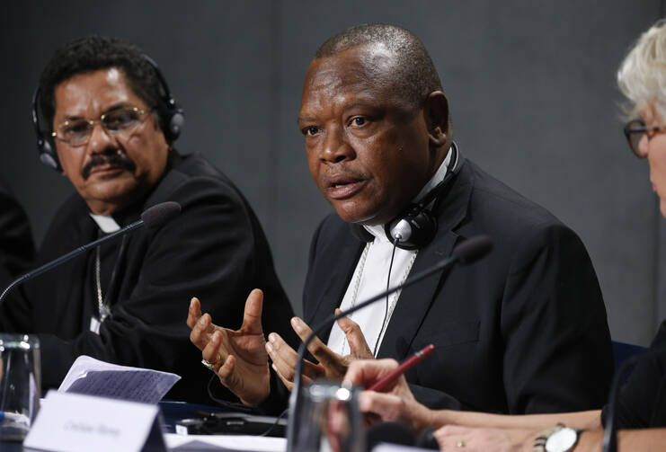  Cardinal Fridolin Ambongo Besungu of Kinshasa, Congo, speaks at a news conference after a session of the Synod of Bishops for the Amazon at the Vatican Oct. 22, 2019. At left is Bishop Karel Choennie of Paramaribo, Suriname. (CNS photo/Paul Haring) 