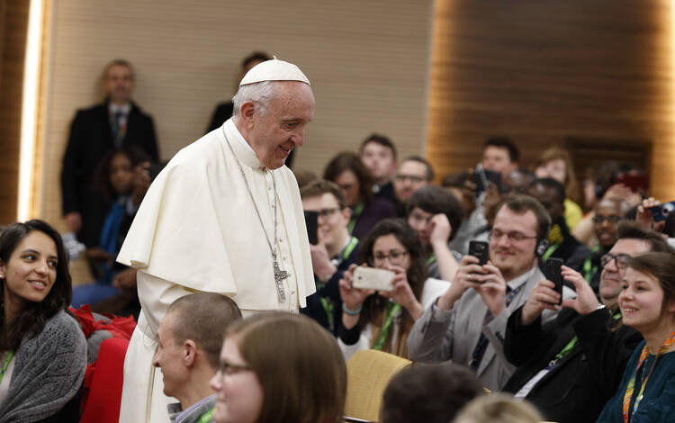 Pope Francis prepares to take a photo with young people at a presynod gathering of youth delegates in Rome March 19. (CNS photo/Paul Haring)