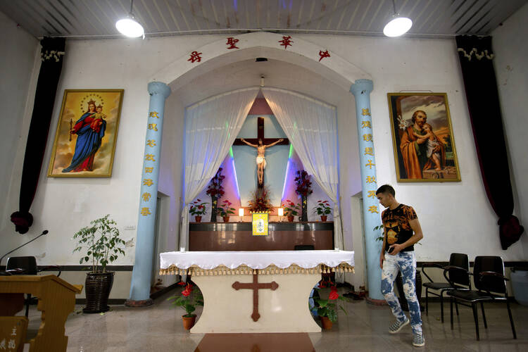 In this July 30, 2015, file photo, a parishioner walks past the altar as members of Lower Dafei Catholic Church hold an impromptu prayer vigil as they wait for Chinese officials to arrive and cut down their church's cross in Lower Dafei Village near Wenzhou in eastern China's Zhejiang Province. (AP Photo/Mark Schiefelbein, File)