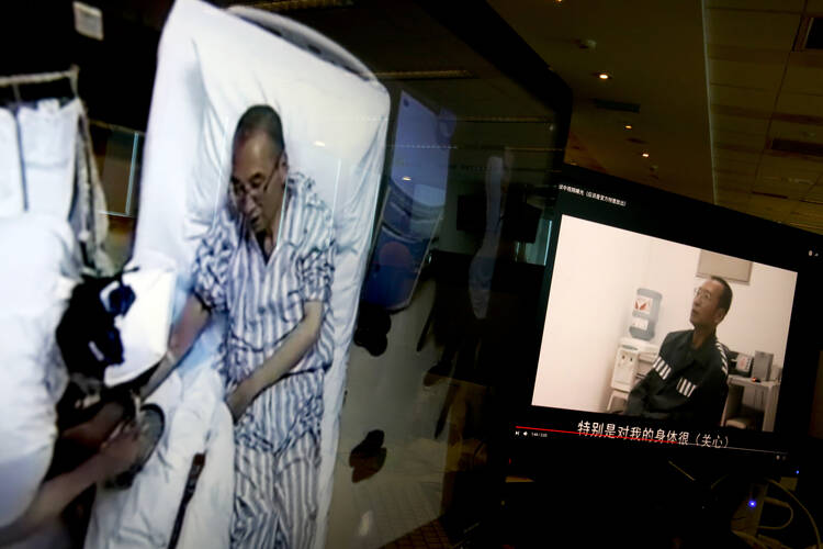Video clips show China's jailed Nobel Peace laureate Liu Xiaobo lying on a bed receiving medical treatment at a hospital, left, and Liu saying wardens take good care of him, on a computer screens in Beijing on June 29. (AP Photo/Andy Wong)