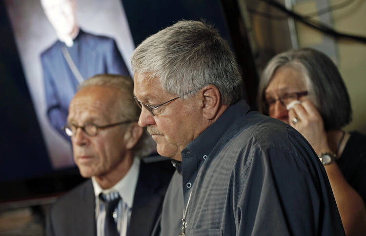 Ron Vasek, center, addresses a news conference along with his wife Patty, right, and attorney Jeff Anderson, left, on May 9, 2017 in St. Paul, Minn. Anderson announced a lawsuit against Bishop Michael Hoeppner of Crookston, Minn., accusing the bishop and diocese of concealing a report of abuse and threatening retaliation against Vasek if he went public. (AP Photo/Jim Mone)
