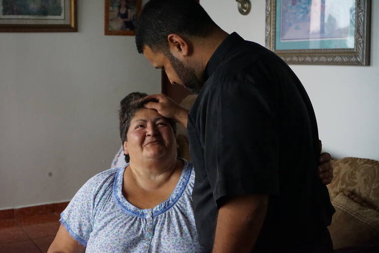 Father Carlos Francis Mendez visits with Rosa Mendez Torres, a woman who suffers from diabetes, in Las Marias, Puerto Rico. (J.D. Long-García)