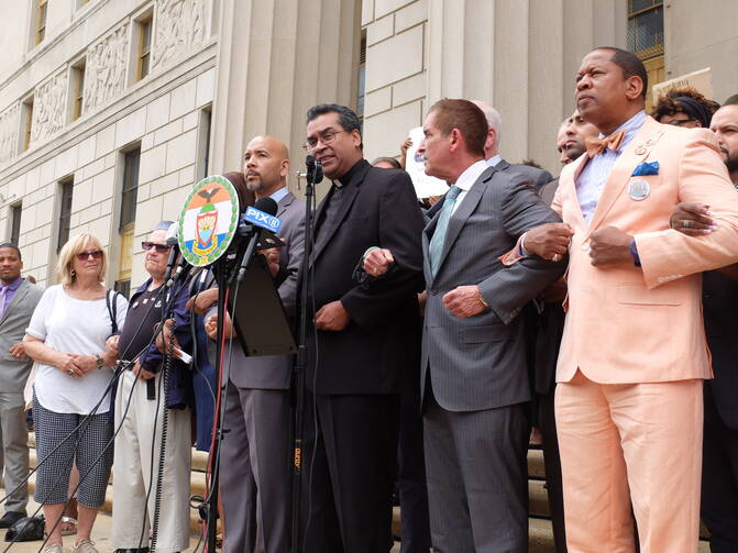 Local elected and religious leaders link arms in prayer, led by Father Eric Cruz, regional director of Catholic Charities Bronx, on the steps of the Bronx County Building in New York on June 22. (Photo: Allyson Escobar)