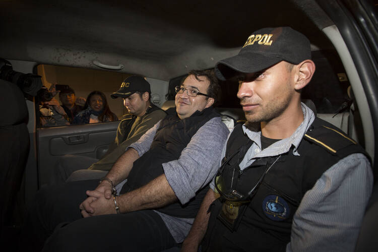 Mexico's former Veracruz state Gov. Javier Duarte, center, is escorted by agents of the local Interpol office inside a police car as they arrive at Guatemala City, early Sunday, April 16, 2017. Duarte, who is accused of running a ring that allegedly pilfered from state coffers, has been detained in Guatemala after six months as a fugitive and a high-profile symbol of government corruption. (AP Photo/Moises Castillo)