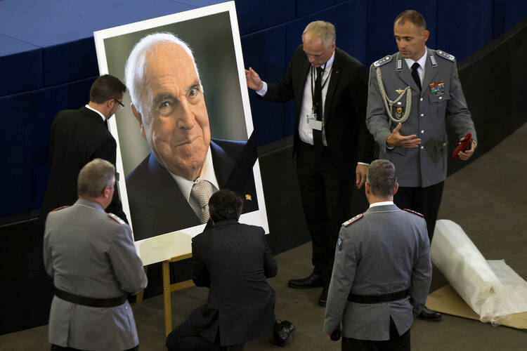 European Parliament employees set up a portrait of former German Chancellor Helmut Kohl before an European ceremony in Strasbourg on July 1. The ceremony was followed by a requiem Mass at the cathedral in Speyer, Germany. (AP Photo/Michel Euler)