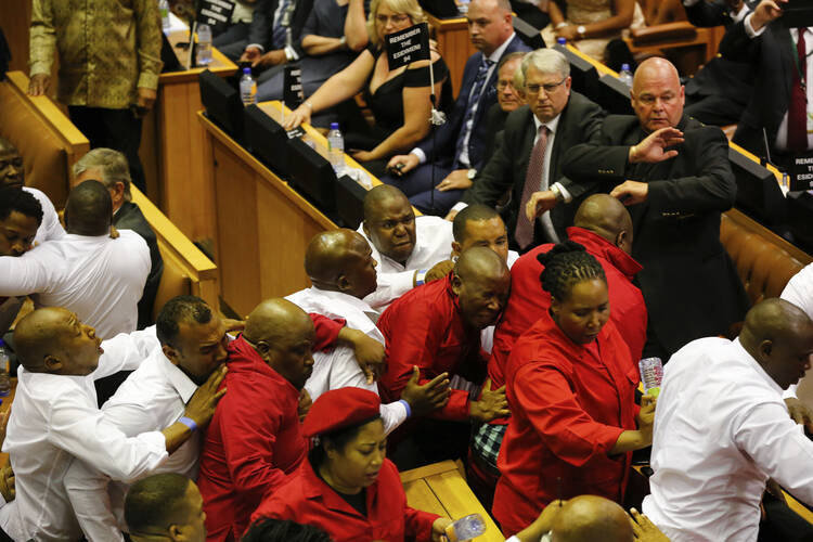 Economic Freedom Fighters in red are forcibly removed from parliament in Cape Town, South Africa, on Feb. 9, 2017. Parliament descended into chaos with opposition lawmakers denouncing President Jacob Zuma as a "scoundrel" and "rotten to the core" because of corruption allegations and then brawling with guards who dragged them out of the chamber. (AP Photo/Sumaya Hisham, Pool)