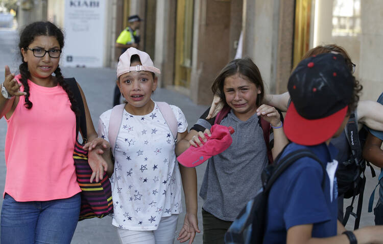 Children, some in tears, are escorted down a road in Barcelona, Spain, Thursday, Aug. 17, 2017. Police in Barcelona say a white van has mounted a sidewalk, struck several people in the city's Las Ramblas district. (AP Photo/Manu Fernandez)