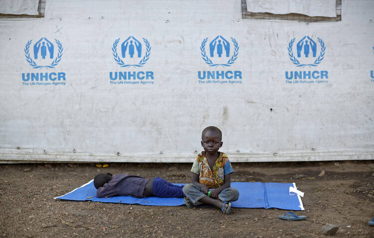  In this Friday, June 9, 2017 file photo, a South Sudanese refugee boy sits on a mat outside a communal tent while his brother sleeps, at the Imvepi reception center, where newly arrived refugees are processed before being allocated plots of land in nearby Bidi Bidi refugee settlement, in northern Uganda. AP Photo/Ben Curtis, File)