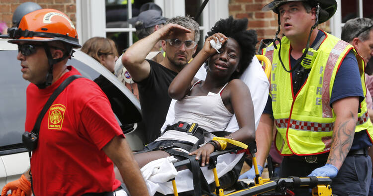 Rescue personnel help an injured woman after a car ran into a large group of protesters after an white nationalist rally in Charlottesville, Va., on Aug. 12. (AP Photo/Steve Helber)