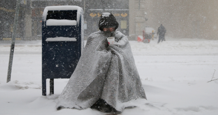 A homeless man asks for money during blizzard-like conditions Feb. 9 in in Boston (CNS photo/Brian Snyder, Reuters).