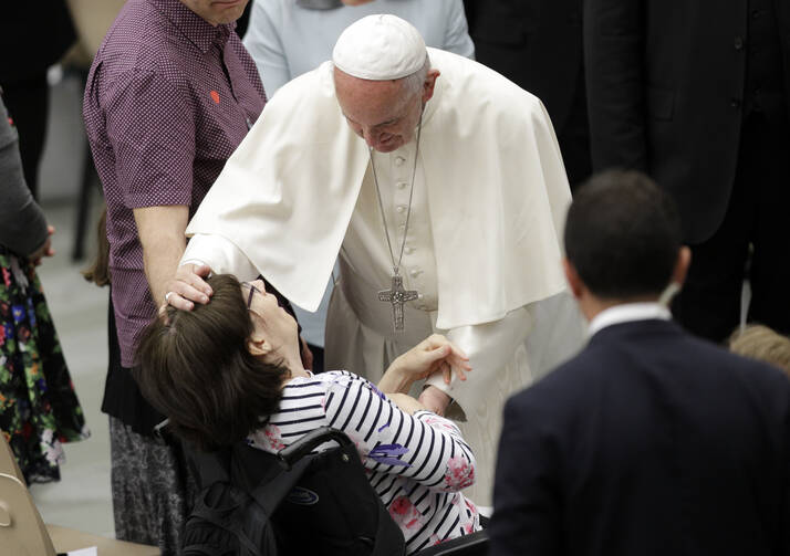 Pope Francis caresses a sick woman during an audience with Huntington's disease sufferers and their families, in the Paul VI Hall, at the Vatican on Thursday, May 18, 2017. (AP Photo/Andrew Medichini)