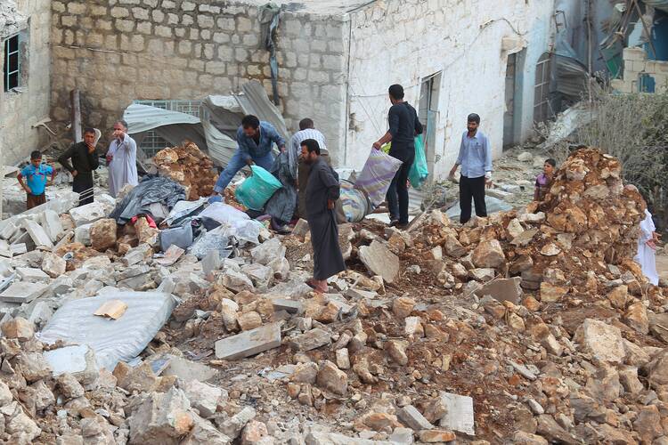 Civilians carry belongings recovered from a site hit by what residents said were airstrikes carried out by the Russian air force in Aleppo, Syria, Oct. 7. (CNS photo/Ammar Abdullah, Reuters)