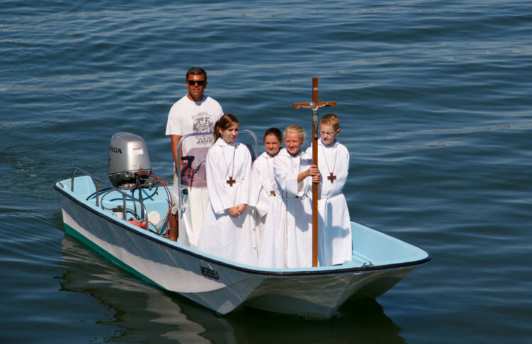 Altar servers from St. Mary of the Assumption at St. Ann's Church in Hull, Mass., approach a pier in August 2013 as part of a festival for the feast of the Assumption of Mary. 