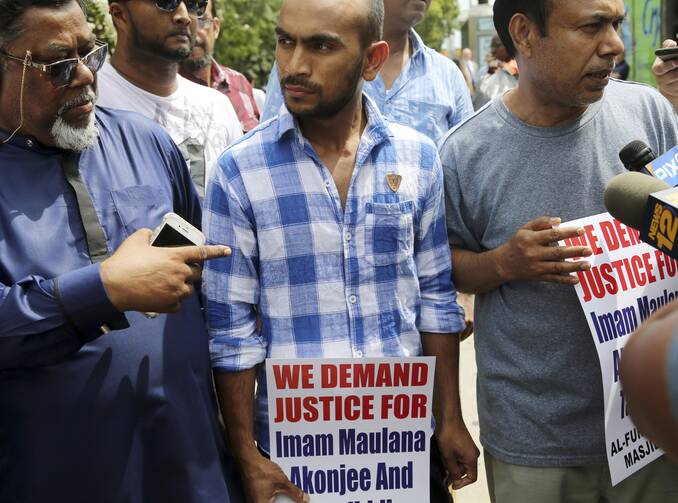 Saif Akonjee, son of Imam Maulana Alauddin Akonjee, center, Mashuk Uddin, brother of Thara Uddin, right, and other members of the community are surrounded by reporters as they arrives to a Queens courthouse in New York, on Aug. 16. (AP Photo/Seth Wenig)