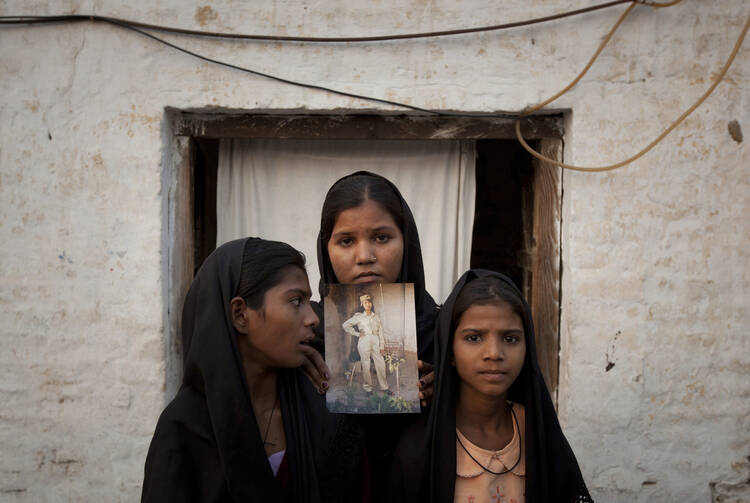 In November 2010, The daughters of Pakistani Christian woman Asia Bibi hold a photo of their mother outside their residence in Ittanwalai, Pakistan. (CNS photo/Adrees Latif, Reuters)