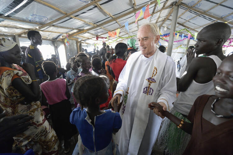 Maryknoll Father Mike Bassano greets people during the sign of peace at Mass April 9 in a makeshift chapel inside a U.N. base in Malakal, South Sudan. (CNS photo/Paul Jeffrey)