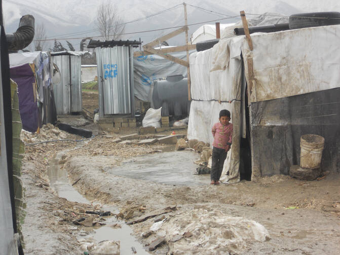 A Syrian child stands barefoot outside a tent Feb. 17 at a camp in Lebanon's Bekaa Valley. This winter's heavy rains have caused the paths between the tents at the settlements to fill with water. (CNS photo/Brooke Anderson)