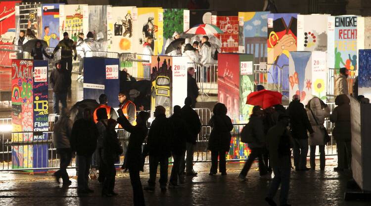 People walk next to colorful giant domino pieces placed along a stretch of the original path of the Berlin Wall Nov. 9, the 20th anniversary of the wall's demise. (CNS photo/Maya Hitij, Reuters) 